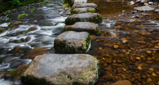 stepping-stones-over-river-and-small-waterfall